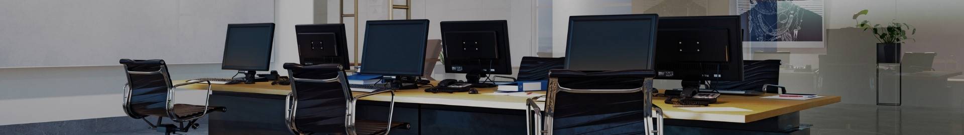 Office room with a long desk and office chairs. The table has computers placed on it.